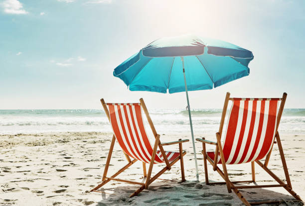 istock Rest, relax and beach chairs with umbrella on sand for vacation, holiday or weekend break. Summer, blue sky and seats in nature with water and ocean for peace, travel or tourism getaway 2157720103