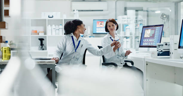 istock Conversation, chemistry and women in lab, teamwork and question with help, advice and cooperation. People, science investigation or researcher in workspace, bottle or testing with experiment or study 2157720331
