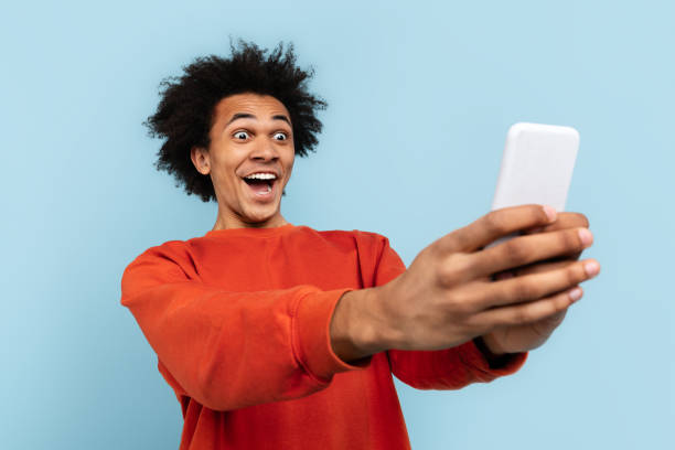 istock Excited man taking selfie with smartphone on blue background 2157720983