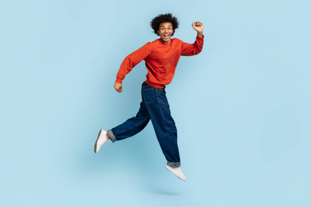 istock Exuberant young man running and smiling on blue background 2157720988