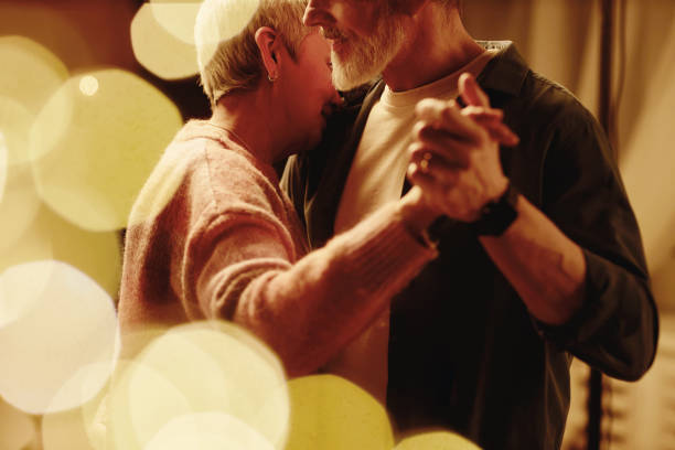Side view of loving senior couple slow dancing and enjoying romantic date night with bokeh effect copy space