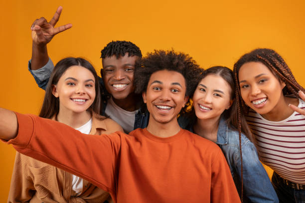 istock Multiethnic friends taking a lively selfie on orange background 2157722374