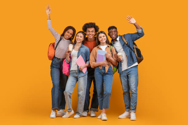 istock Happy students waving goodbye or greeting on orange background 2157722409