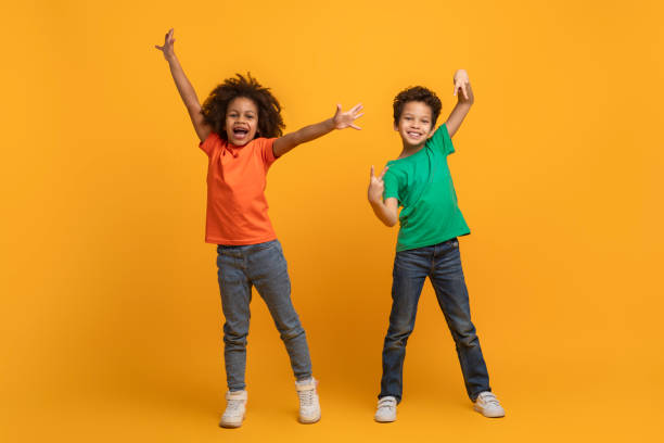 istock Cheerful Young Siblings Celebrating With Joyful Gestures Against Yellow Background 2157722632