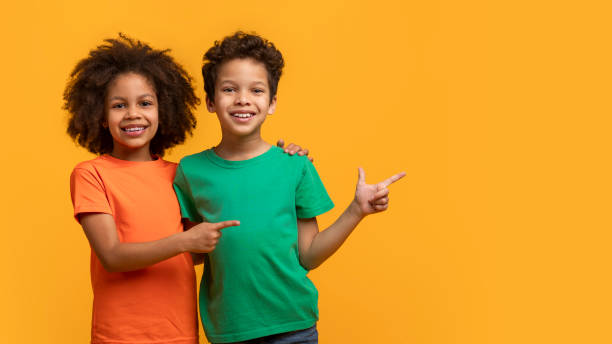istock Two Smiling Children in Colorful T-Shirts Pointing at Copy Space 2157722645