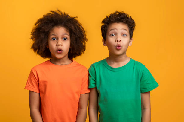 istock Two Surprised Children With Expressive Faces Standing Against Yellow Background 2157722646