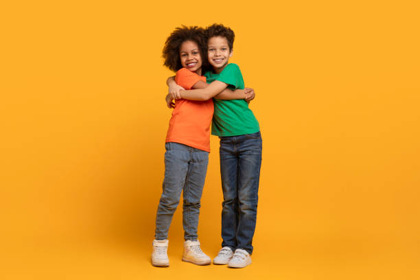 istock Two African American Children Hugging on Yellow Background 2157722647