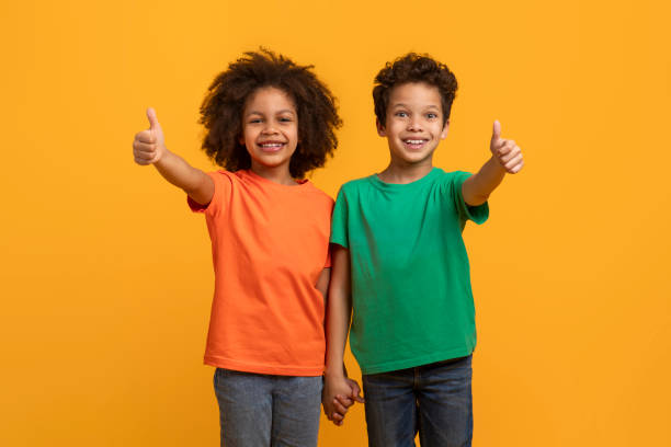 istock Two Young Children Giving Thumbs Up on Yellow Background 2157722652