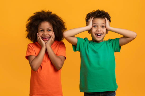 istock Two Joyful Children Expressing Surprise and Delight on Yellow 2157723067