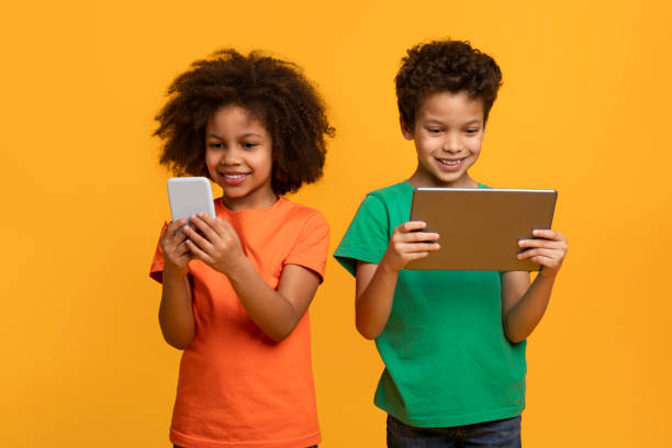 istock Two Young Children Holding Tablet and Phone 2157723165