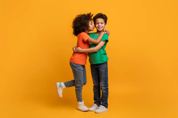 istock Two Children Hugging Each Other on a Yellow Background 2157723182