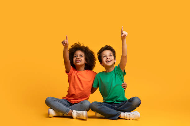 istock Two Children Sitting on the Floor With Arms Raised 2157723193