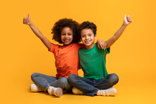 istock Two Children Sitting on Floor With Arms Raised 2157723201