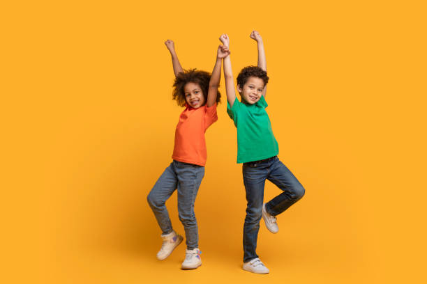 istock Two African American Children Jumping on Yellow Background 2157723205