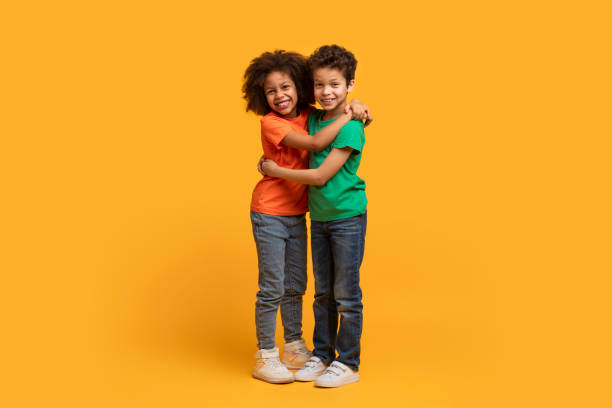 istock Two Children Hugging on a Yellow Background 2157723238