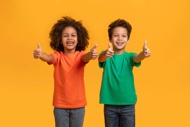 Two Children Giving Thumbs Up on an Orange Background