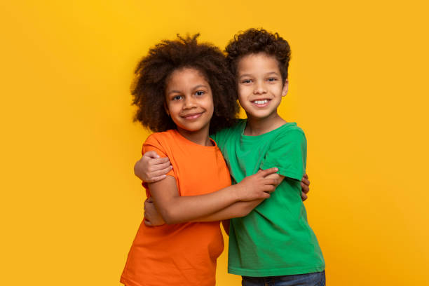 istock African American siblings hugging smiling on yellow background 2157723276