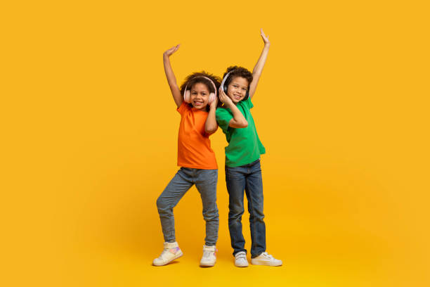 istock Siblings dancing with raised arms on yellow background 2157723277