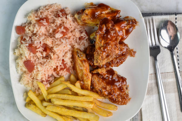 chicken wings served  with rice and tomatoes  with a side of fries