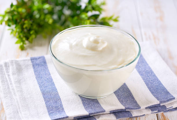 istock natural organic yogurt in a bowl with spoon on a white table, selective focus. 2157729245