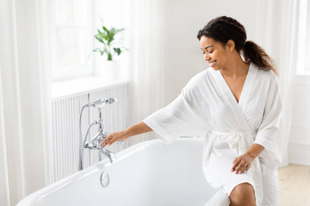 istock Elegantly reaching for bath faucet in robe 2157729729