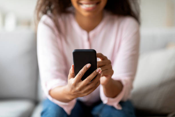 istock Smiling black lady texting on her smartphone 2157730020