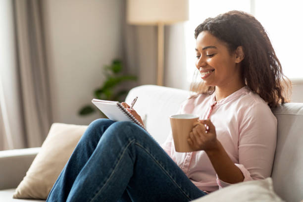 African american woman writing in notebook at home
