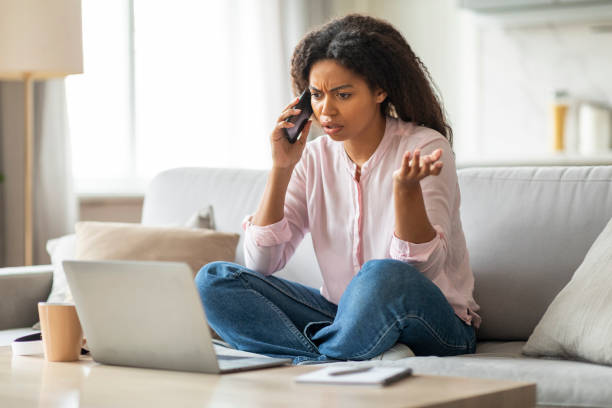 istock Concerned woman on phone looking at laptop 2157730052
