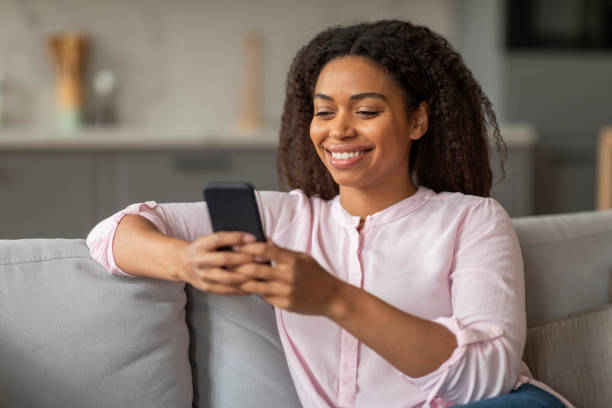 istock Happy young black woman using smartphone at home 2157730066