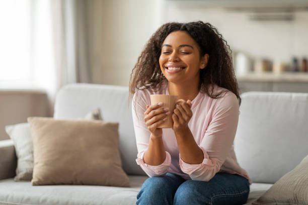 istock Positive young black woman sitting on couch, drinking coffee 2157730112