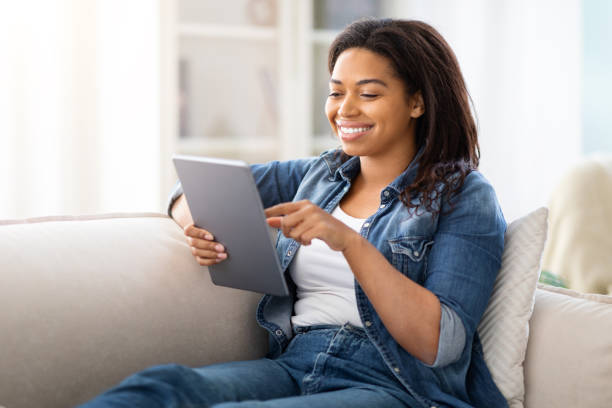 istock Pretty Woman Sitting on Couch Looking at Tablet 2157730296
