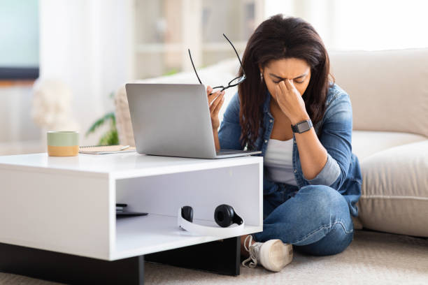 istock Woman Sitting on Floor Using Laptop, Rubbing Eyes 2157730325