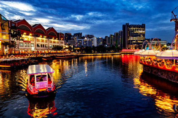 Night view of Singapore Clarke Quay with vessel for river cruises passing under the bridge