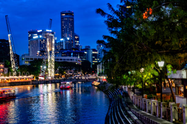 Night view of Singapore Clarke Quay with vessel for river cruises passing under the bridge