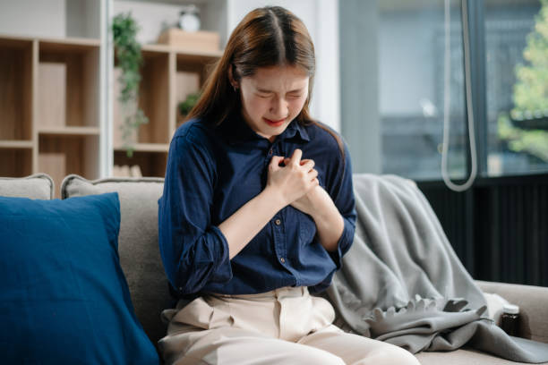 istock Young Asian woman suffering from flu symptoms, covered with a blanket on a sofa. Concept of illness, healthcare, and recovery. 2157736757
