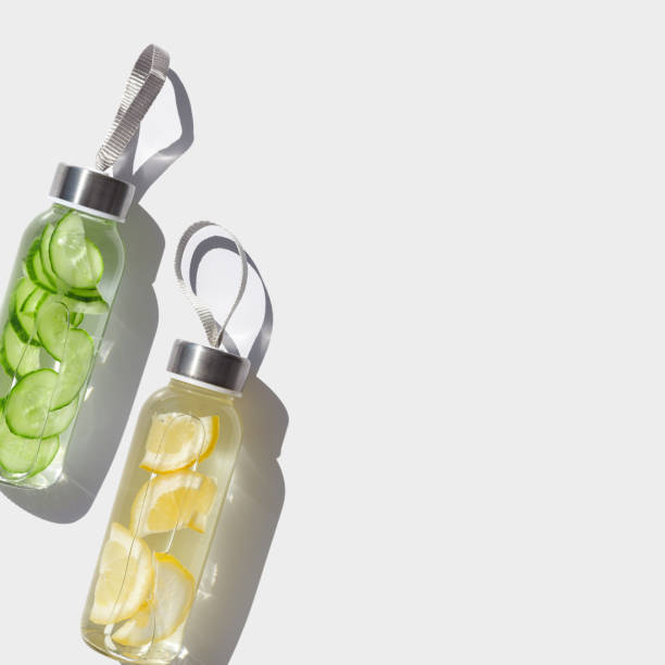istock Cleansing and refreshing Lemon, cucumber water drink detox, shadow at sunlight on white at sunlight. Wellness, alkaline diet, eating healthy concept. Stylish glass reusable water bottle, top view 2157736997