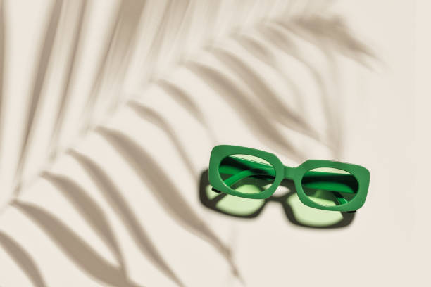 istock Trendy sunglasses with green Frame on neutral beige background, copyspace, beach vibes, summertime mood, palm leaf shadow, summer fashion vivid glasses. Minimal top view of eyeglasses 2157737034