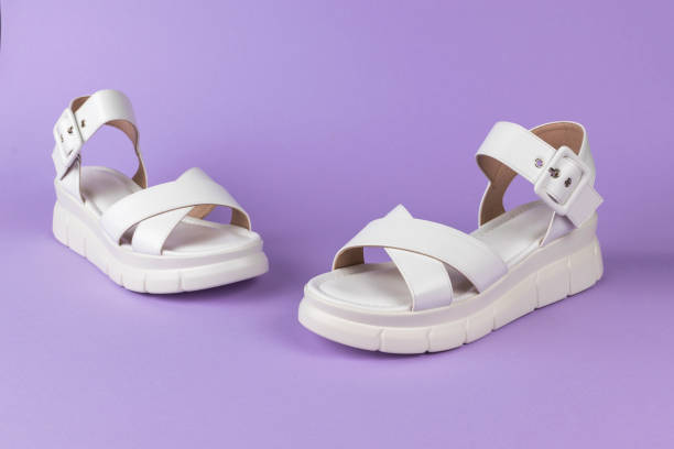 istock ** Stylish White Sandals with Chunky Platform Soles Against a Purple Background 2157737135