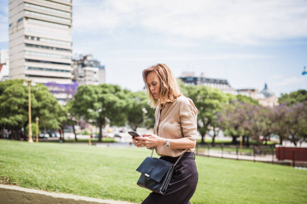 istock Businesswoman Walking in City Park While Using Smartphone 2157738667