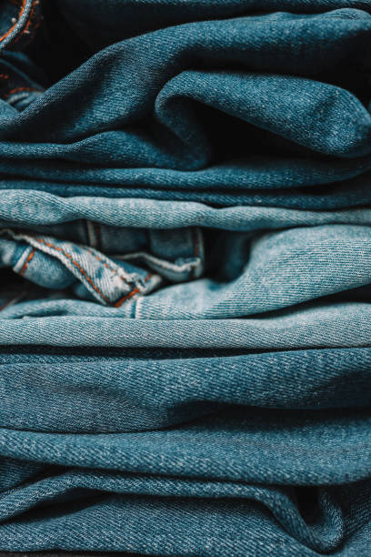 istock Stack of Various Shades Of Blue Jeans On White Background Denim jeans texture 2157740730