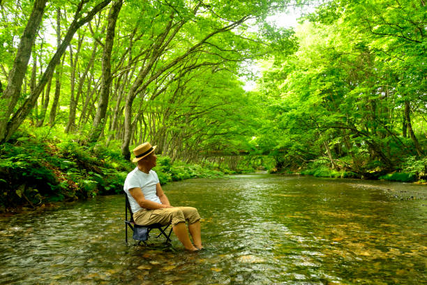 istock Senior man enjoying the coolness of a mountain stream 2157741012