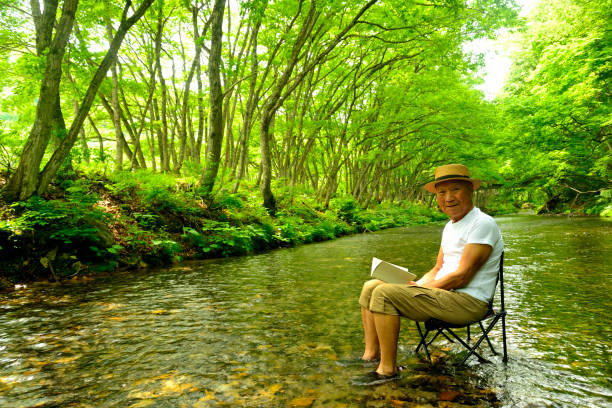 istock Senior man enjoying the coolness of a mountain stream 2157741032