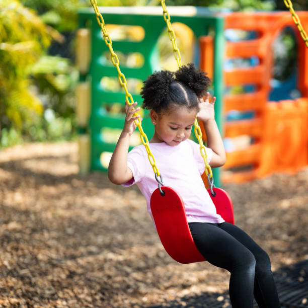 istock Little girl using a swing on a daycare playground 2157743064