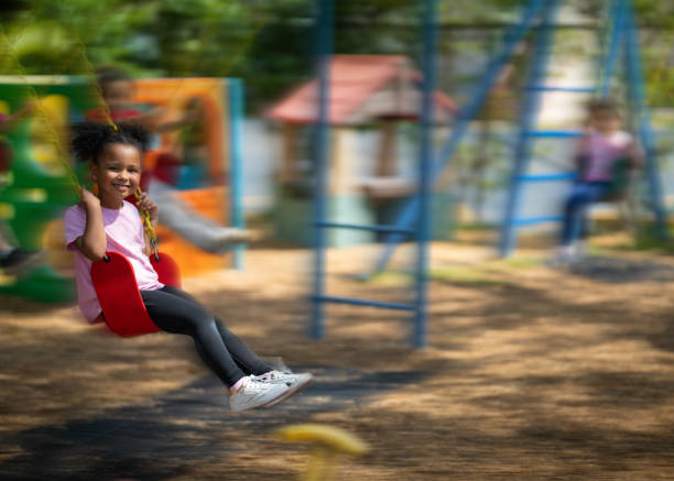 istock Little girl using a swing on a daycare playground 2157743076