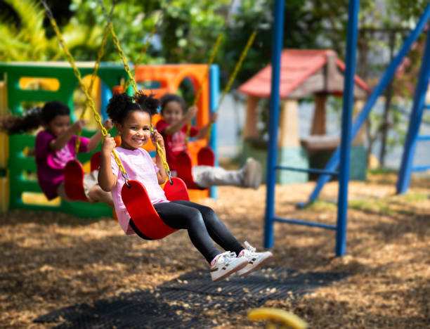 istock Little girl using a swing on a daycare playground 2157743114