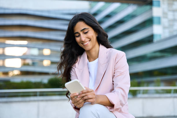 istock Smiling young middle eastern Israel businesswoman using smartphone mobile phone online app for work at office building. Successful 20s happy indian or arabic woman in business suit holding cellphone 2157749314