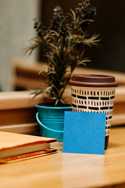 A book, flowers, a disposable cup and a blue note in the cafe