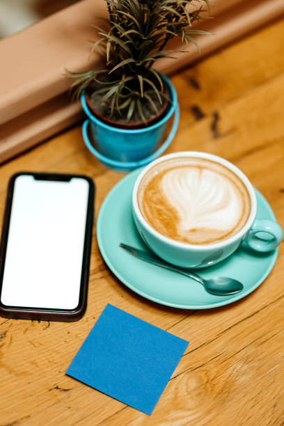 A book, flowers, espresso, a mobile phone and a blue note in a cafe