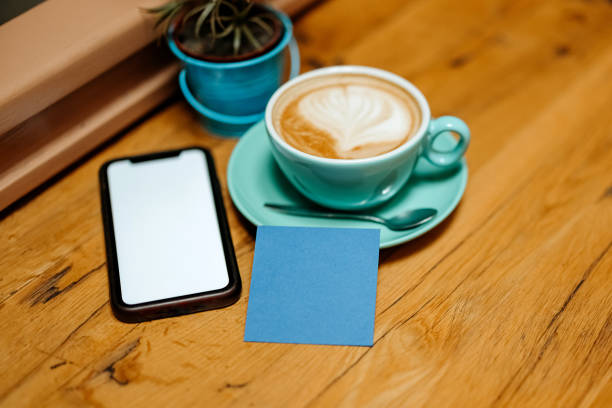 A book, flowers, espresso, a mobile phone and a blue note in a cafe