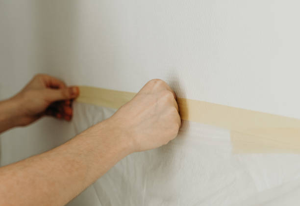 istock A young man puts adhesive tape on the wall. 2157752110